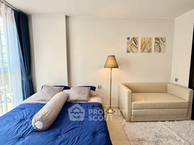 Modern bedroom with cozy bed, stylish sofa, and elegant decor in a bright apartment.