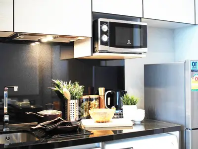 Modern kitchen with sleek appliances and stylish decor, featuring a microwave, fridge, and elegant countertop.