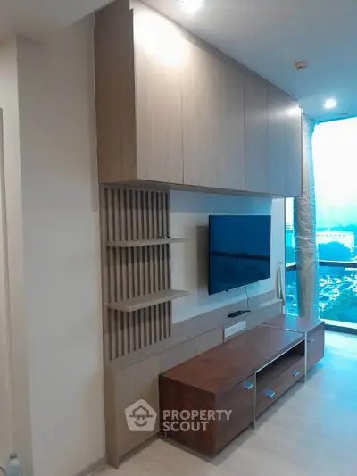 Modern living room with stylish wooden entertainment unit and large window view.