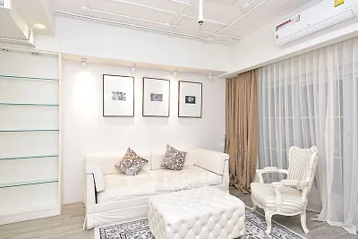 Elegant living room with white sofa, armchair, and decorative art on walls.