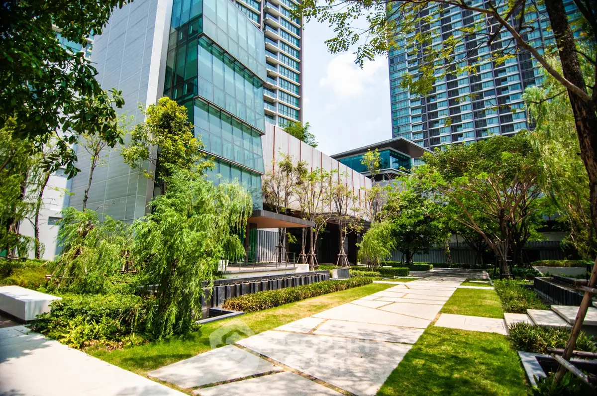 Luxurious modern building with lush landscaped garden and sleek architectural design in urban setting.