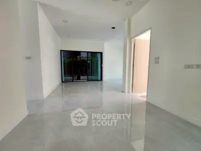 Spacious modern living room with large sliding glass doors and glossy tile flooring.