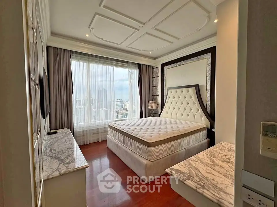 Luxurious bedroom with city view, elegant decor, and plush furnishings in high-rise apartment.