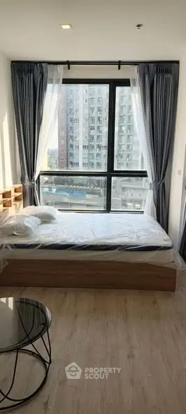 Bright bedroom with large window and modern furnishings in urban apartment