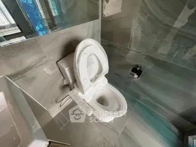 Modern bathroom with sleek tile design and high-tech toilet in a contemporary apartment.