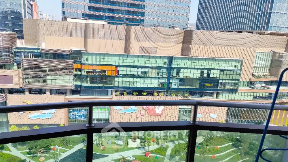 Stunning urban view from a high-rise balcony overlooking modern architecture and landscaped gardens.
