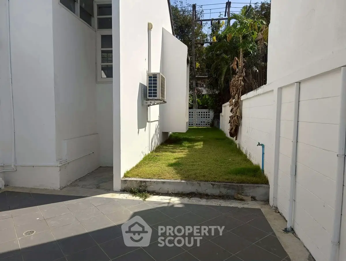 Charming small garden area with air conditioning unit and tiled patio, perfect for relaxation.
