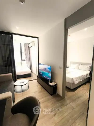Modern apartment interior with cozy living room and bedroom, featuring sleek furniture and natural light.