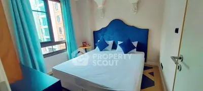 Charming bedroom with elegant blue accents and large window in modern apartment.
