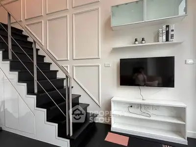 Modern living room with sleek staircase and mounted TV, showcasing stylish interior design.