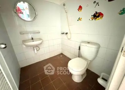 Compact bathroom with white tiles and round mirror, featuring a shower and toilet.