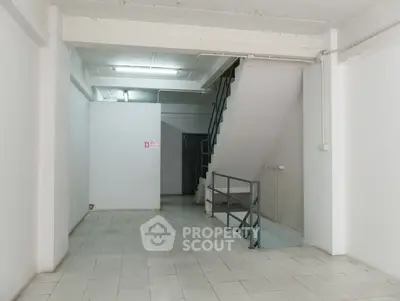 Spacious interior with staircase and tiled flooring, ideal for storage or utility use.