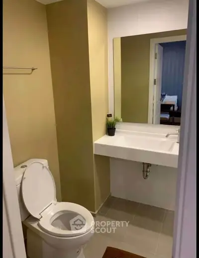 Modern bathroom with sleek design and neutral tones, featuring a large mirror and contemporary fixtures.