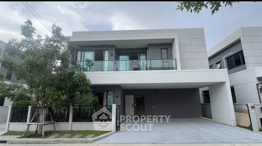 Modern two-story house with sleek design and spacious driveway in a serene neighborhood.