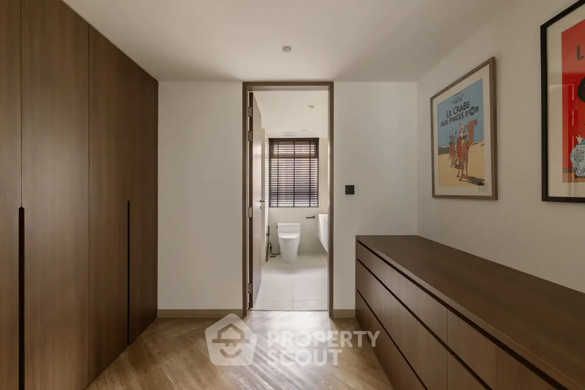 Modern hallway with wooden cabinets leading to a stylish bathroom