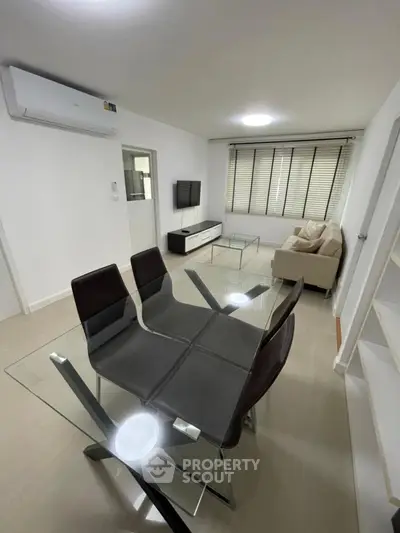 Modern living room with glass dining table and cozy seating area, perfect for relaxation and entertainment.