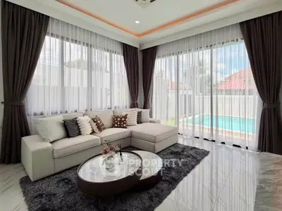 Luxurious living room with pool view, featuring elegant decor and abundant natural light.