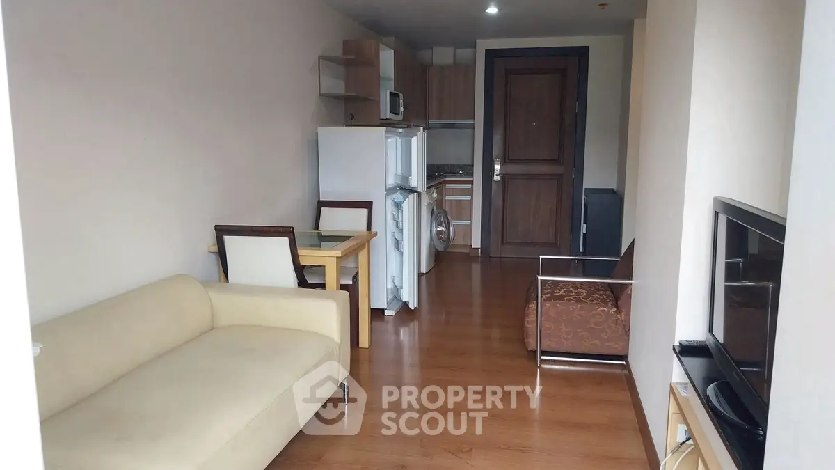 Cozy living room with modern furniture and compact kitchen in open layout apartment.