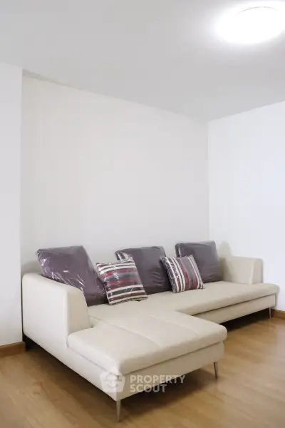 Modern living room with stylish white sofa and decorative pillows on wooden flooring.