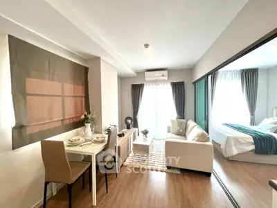 Modern open-plan living room with dining area and bedroom, featuring stylish decor and natural light.