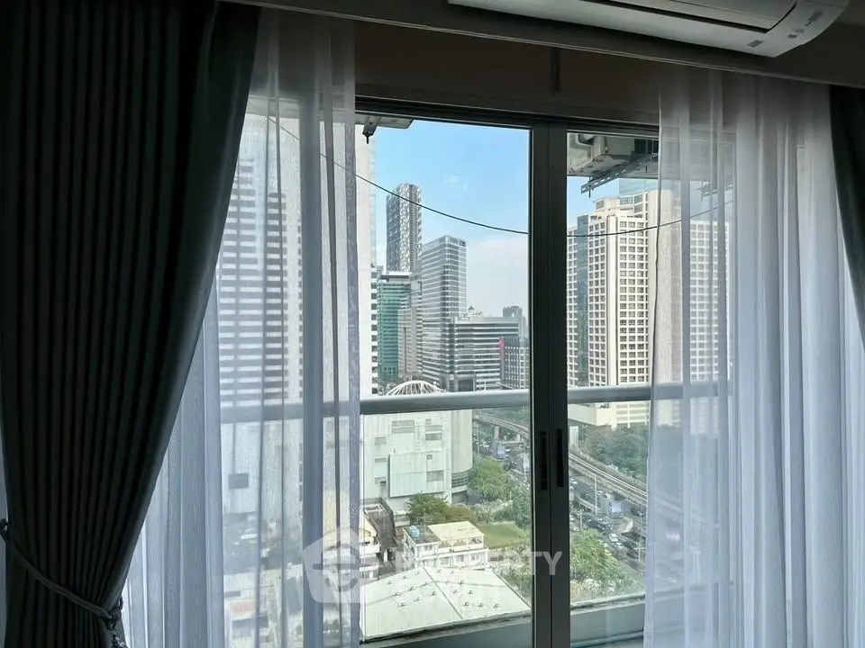Stunning city view from high-rise apartment window with elegant curtains.