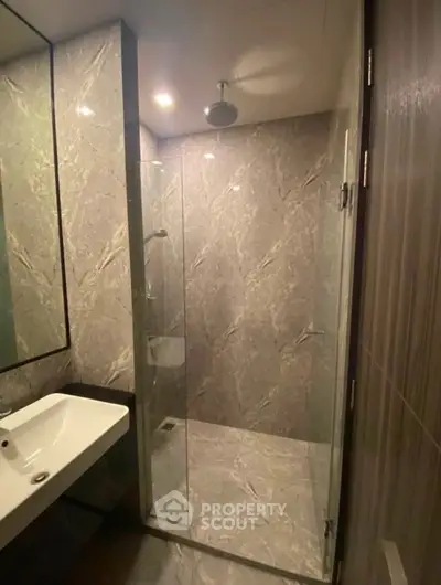 Modern bathroom with sleek marble tiles and glass shower enclosure