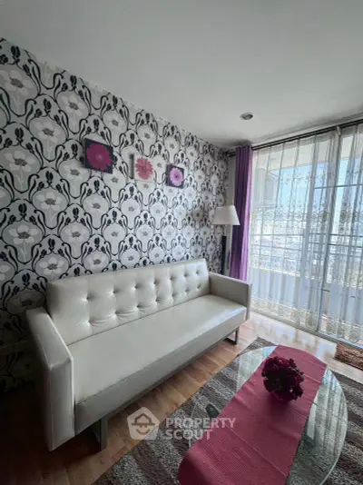 Chic living room with floral wallpaper and modern white sofa, featuring a glass coffee table and balcony view.