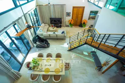 Luxurious open-plan living room with high ceilings and elegant decor, featuring a modern staircase and ample natural light.
