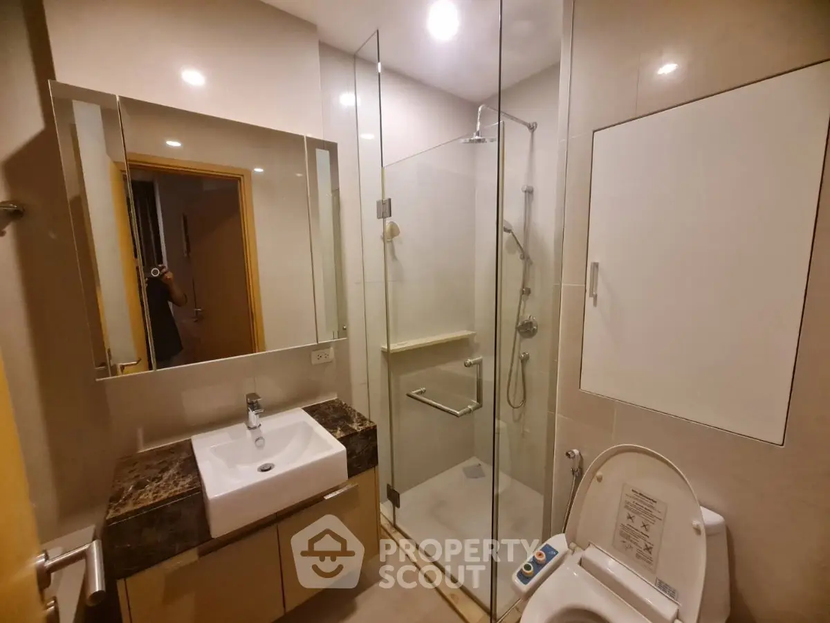 Modern bathroom with glass shower and sleek vanity in contemporary apartment.