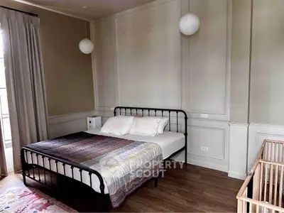 Cozy bedroom with elegant decor and natural light, featuring a stylish bed and crib.