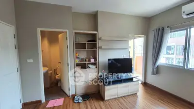 Modern living room with TV, wooden flooring, and balcony access