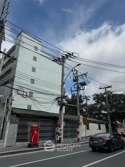 Urban street view with building exterior and power lines under a clear blue sky.