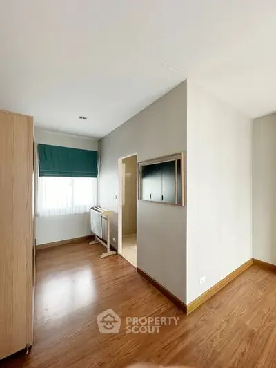 Spacious bedroom with wooden flooring and natural light, perfect for cozy living.