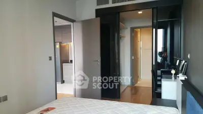 Modern bedroom with sleek design and open closet, adjacent to a stylish kitchen.