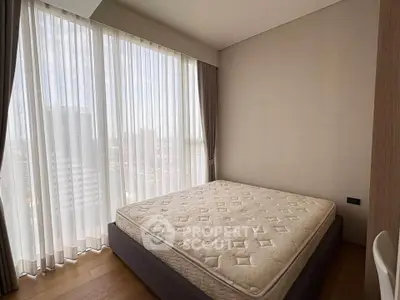 Spacious bedroom with large windows and natural light in modern apartment.