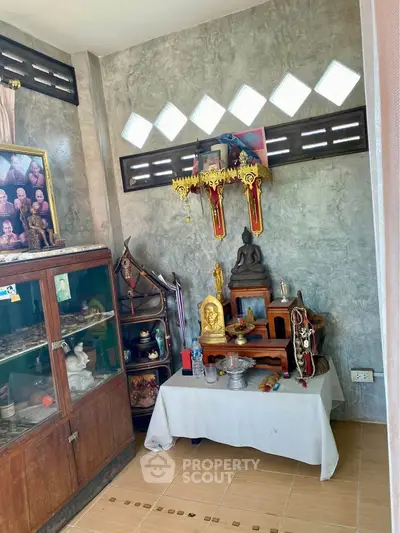 Cozy corner with religious artifacts and wooden cabinet in a serene home setting.
