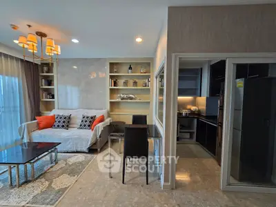 Modern living room with cozy sofa, elegant lighting, and sleek kitchen in open layout apartment.