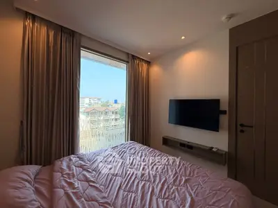 Cozy bedroom with large window offering city view and wall-mounted TV.
