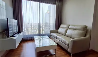Modern living room with sleek furniture and city view through large window.