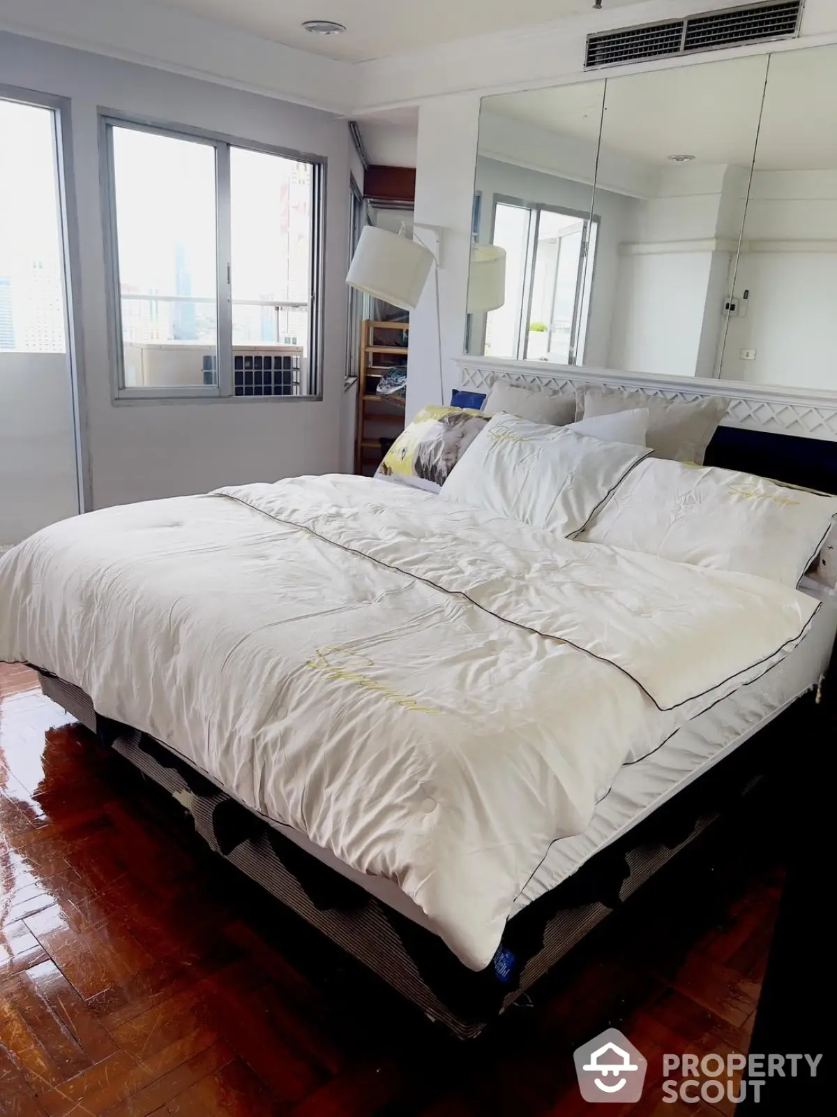 Spacious bedroom with large windows and mirrored wall in modern apartment