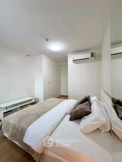 Modern bedroom with cozy bedding and air conditioning in a minimalist design.