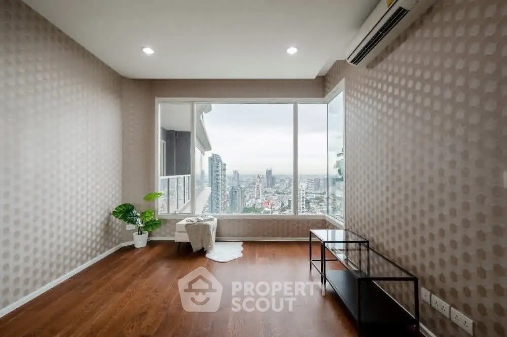 Spacious living room with large window offering stunning city view, modern decor, and wooden flooring.