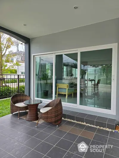 Charming patio with wicker chairs and glass doors leading to modern interior