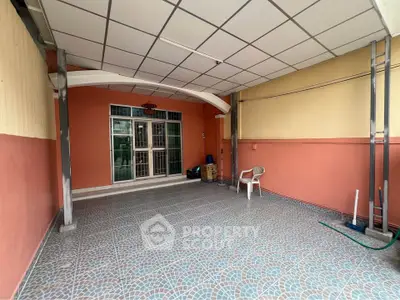 Spacious covered patio with tiled flooring and seating area, perfect for outdoor relaxation.