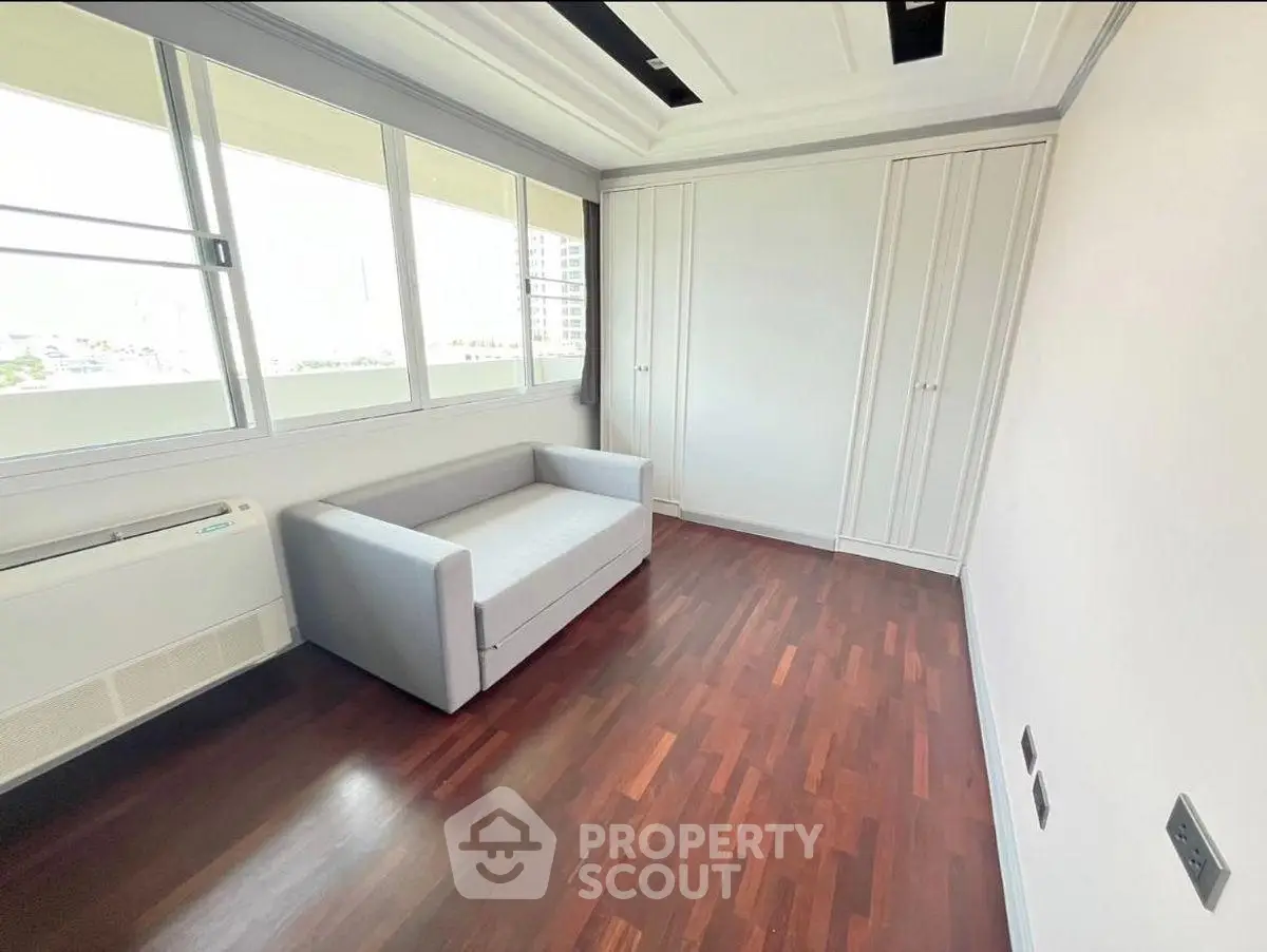 Bright room with wooden flooring, large windows, and a modern sofa bed, perfect for a cozy living space.