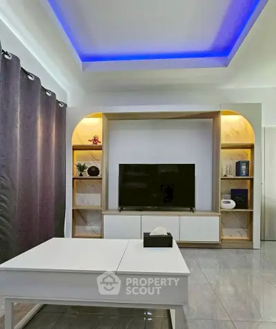 Modern living room with stylish ceiling lighting and sleek TV setup.