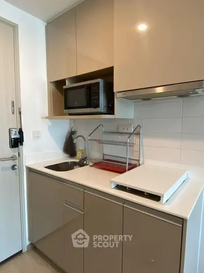 Modern kitchen with sleek cabinetry and built-in microwave in a compact apartment.