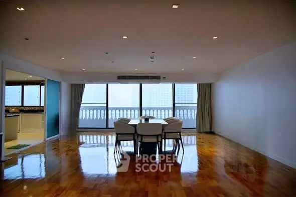 Spacious living room with polished wooden floors and city view balcony.