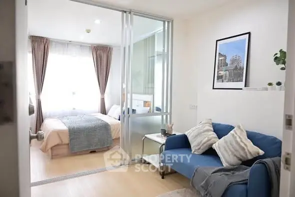 Modern studio apartment with cozy living area and bedroom separated by glass partition.