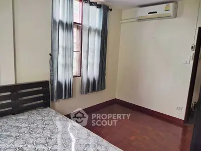 Cozy bedroom with wooden flooring and air conditioning in a bright apartment.